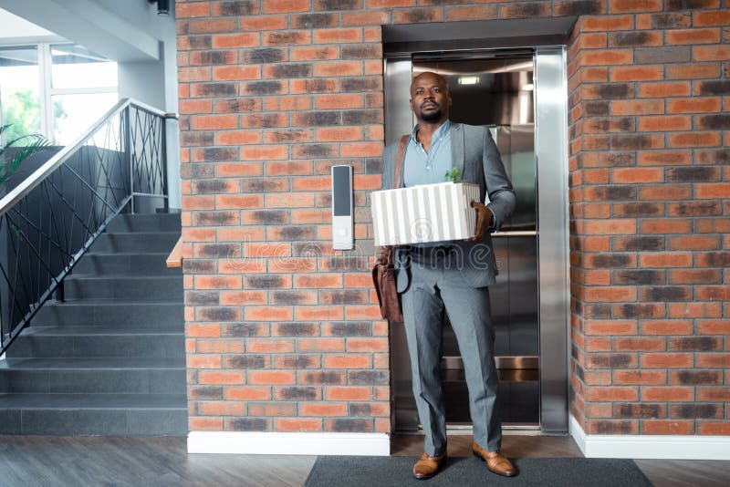Работник нося серое положение костюма в лифте после увольнятьый стоковые фото