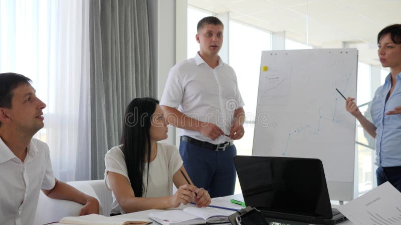 Работник 2 около whiteboard обсуждая развитие биснеса в форму диаграммы