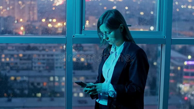 работница, работающая сверхурочно, стоящая у телефона сток-видео