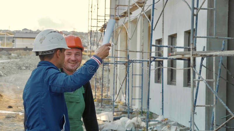 Рабочий-строитель и инженер говоря на месте строительной площадки стоковое изображение rf