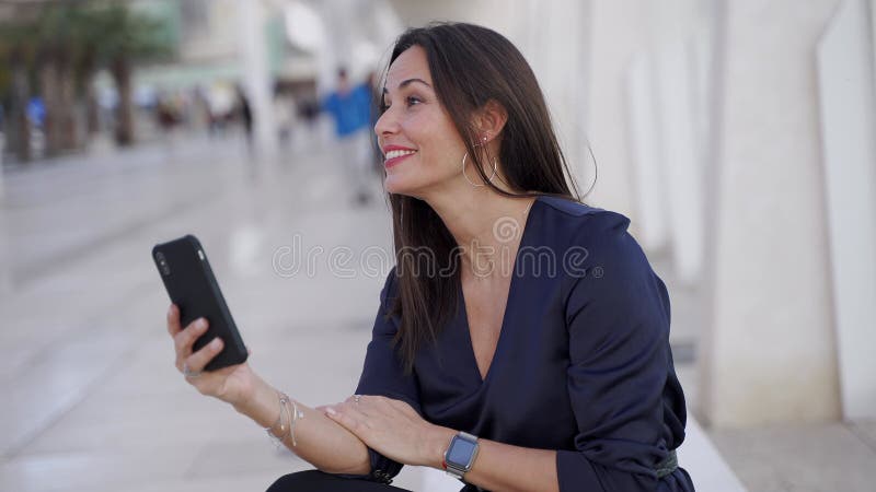 радостная латиноамериканка пользуется смартфоном на улице видеоматериал