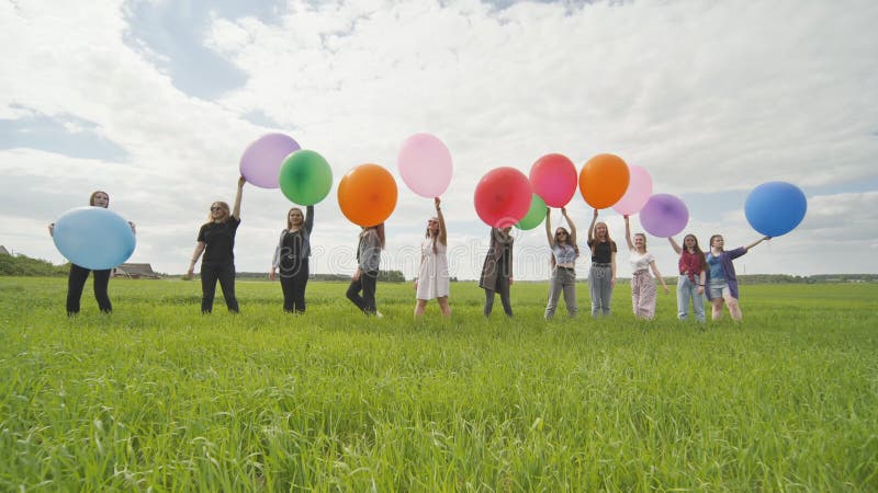 радостные девушки стоят на поле с большими шариками и красочными шариками.