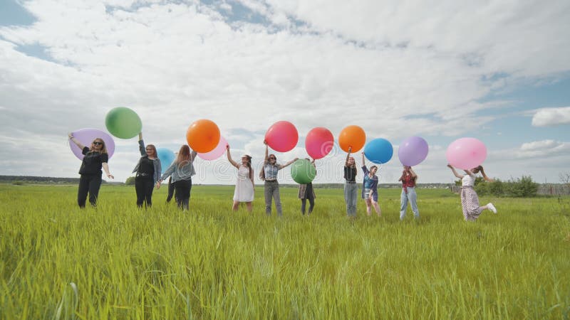 радостные девушки стоят на поле с большими шариками и красочными шариками.