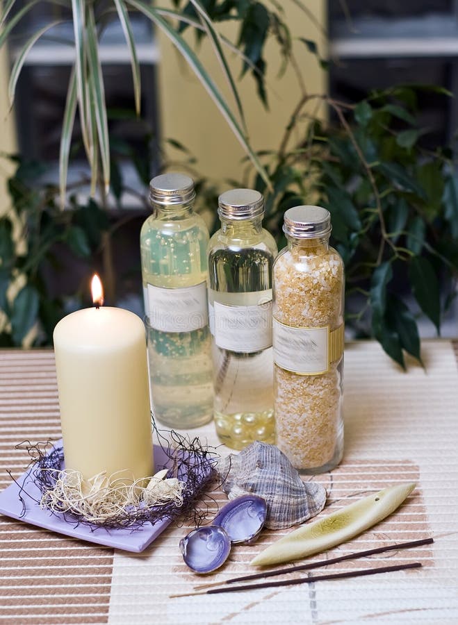 A spa composition cnsisting of three bottles and a pillar candle with some sea elements. A spa composition cnsisting of three bottles and a pillar candle with some sea elements.