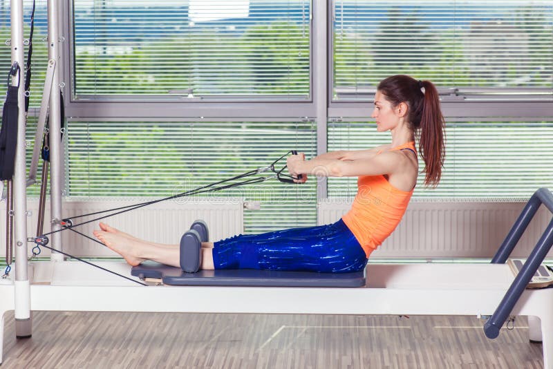 Разминка реформатора Pilates работает женщину на спортзале крытом стоковое изображение rf Разминка реформатора Pilates работает женщину на спортзале крытом стоковое изображение rf