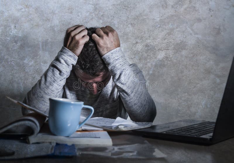 Разочарованный и усиленный молодой человек студента колледжа работая с чувством стола блокнота и портативного компьютера учебника стоковые изображения rf