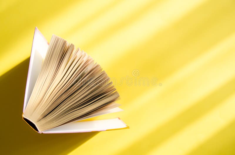 Раскрытая книга на желтой предпосылке в ярком солнце Концепция образования, чтения, приобретения записывает скопируйте космос стоковая фотография rf Раскрытая книга на желтой предпосылке в ярком солнце Концепция образования, чтения, приобретения записывает скопируйте космос стоковая фотография rf