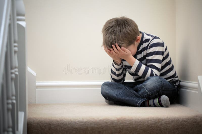 Upset problem child with head in hands sitting on staircase concept for childhood bullying, depression stress or frustration. Upset problem child with head in hands sitting on staircase concept for childhood bullying, depression stress or frustration