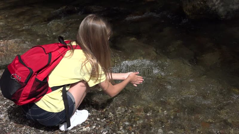 ребенок моет руки в речной воде, играя в весенние водопад-туристки, походящие в поход в горный экскурсию акции видеоматериалы