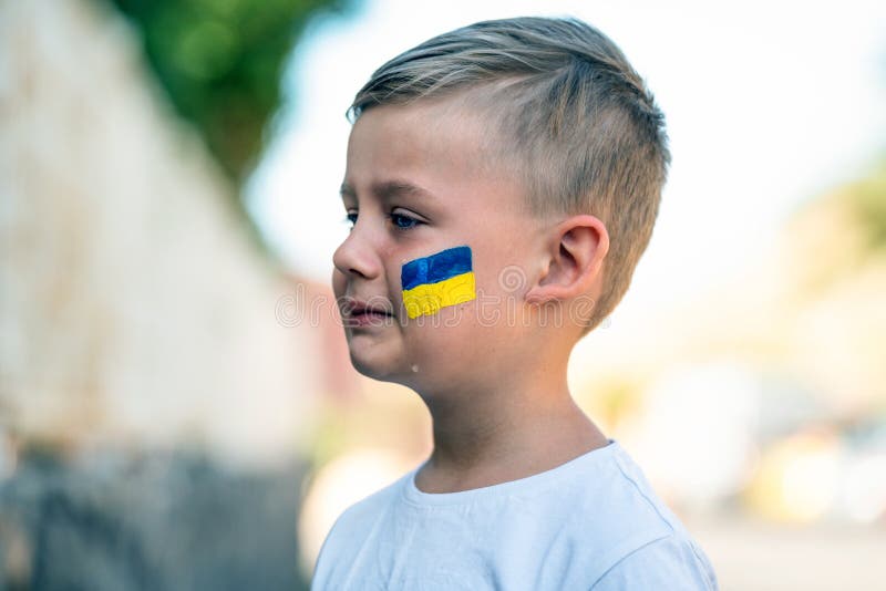 ребенок против войны. расстроенный украинский мальчик с желтым флагом на лице, плачущий, протестуя против военного конфликта. эвак стоковое изображение rf