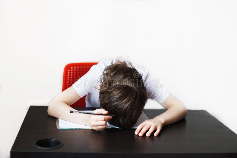 Ребенок учится. Мальчик устал от домашних заданий. Ребенок сидит и делает домашнее задание стоковая фотография rf