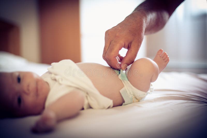 Close-up of mother changing baby`s diaper. Focus is on hand. Close up. Close-up of mother changing baby`s diaper. Focus is on hand. Close up.