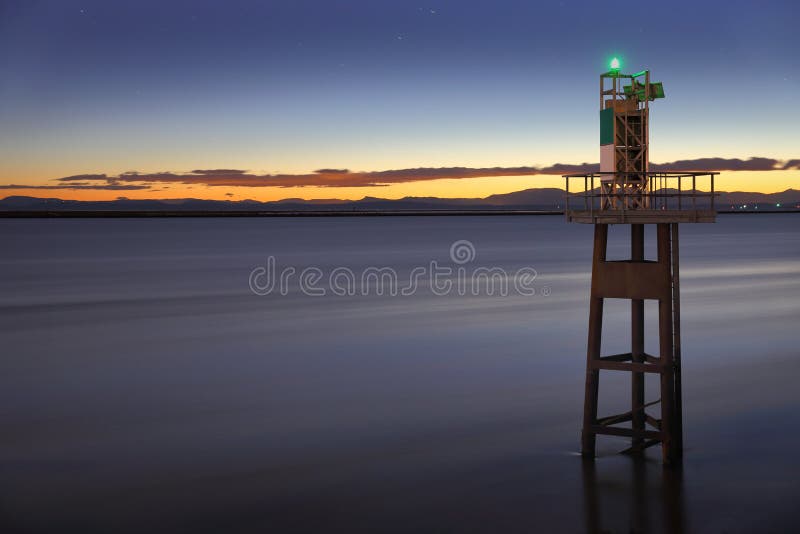 A long exposure of a marine navigation aid near the mouth of the Fraser River. Georgia Strait and Vancouver Island in the background. British Columbia, Canada, near Vancouver. A long exposure of a marine navigation aid near the mouth of the Fraser River. Georgia Strait and Vancouver Island in the background. British Columbia, Canada, near Vancouver.