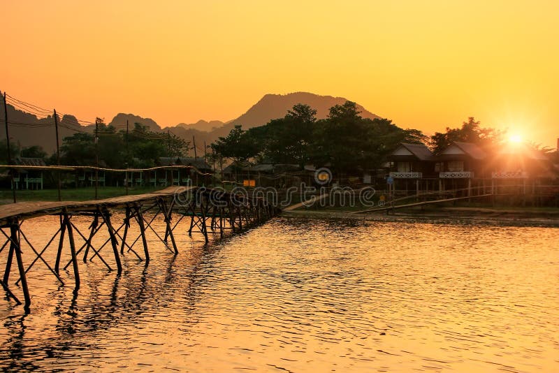 Река песни Nam с деревянным мостом на заходе солнца в Vang Vieng, Лаосе стоковая фотография rf Река песни Nam с деревянным мостом на заходе солнца в Vang Vieng, Лаосе стоковая фотография rf