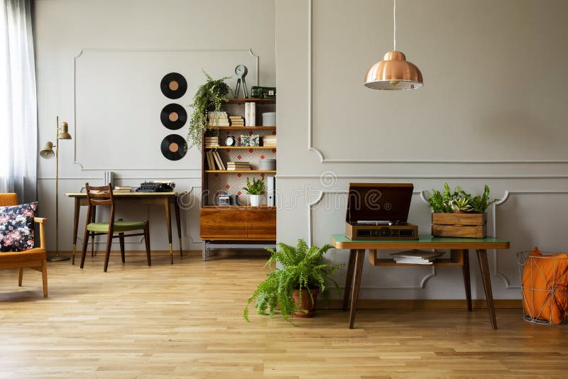 Record player and plant on wooden table in grey apartment interior with lamp and vinyl. Real photo concept. Record player and plant on wooden table in grey apartment interior with lamp and vinyl. Real photo concept
