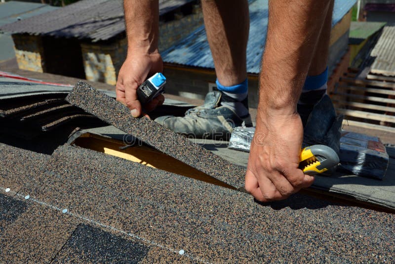 Ремонт толя от гонт Войлок или битум толя вырезывания Roofer во время делать водостойким работают Гонт крыши - толь стоковое фото rf Ремонт толя от гонт Войлок или битум толя вырезывания Roofer во время делать водостойким работают Гонт крыши - толь стоковое фото rf