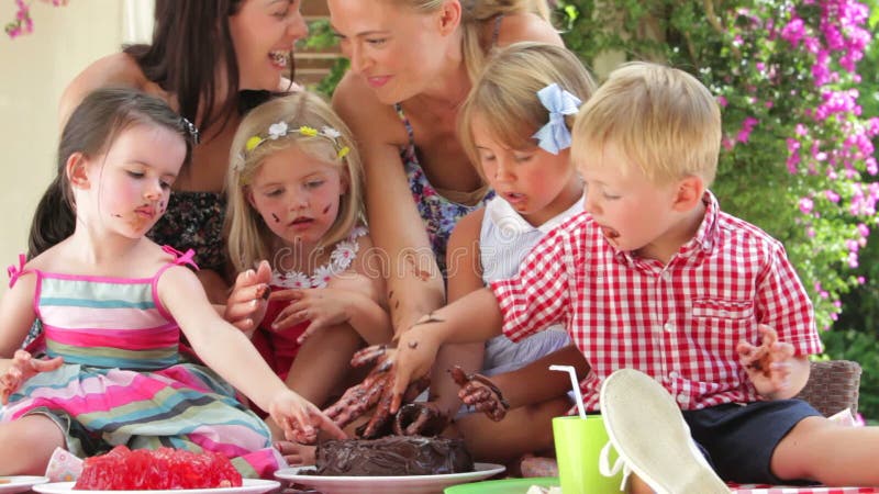 Родители и дети наслаждаясь шоколадным тортом на партии