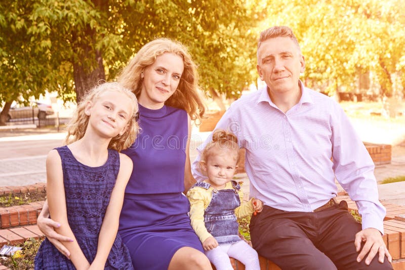 Родители с 2 маленьких дочерей в парке. Портрет семьи. Образ жизни природы стоковое фото