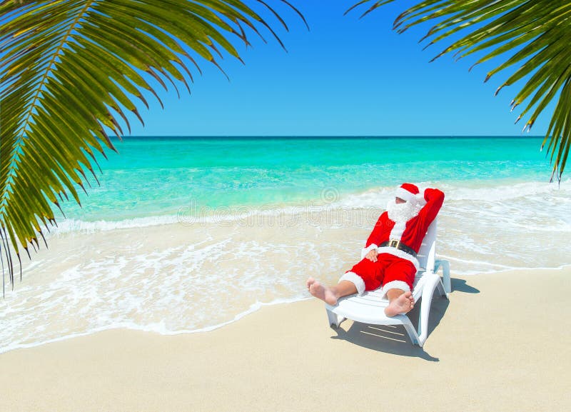 Рождество Санта Клаус ослабляет в sunlounger на тропическом песочном Palm Beach стоковая фотография