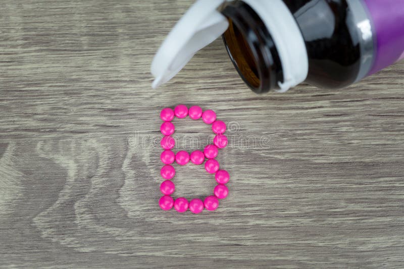 Розовые пилюльки формируя форму к алфавиту b на деревянной предпосылке стоковая фотография rf Розовые пилюльки формируя форму к алфавиту b на деревянной предпосылке стоковая фотография rf
