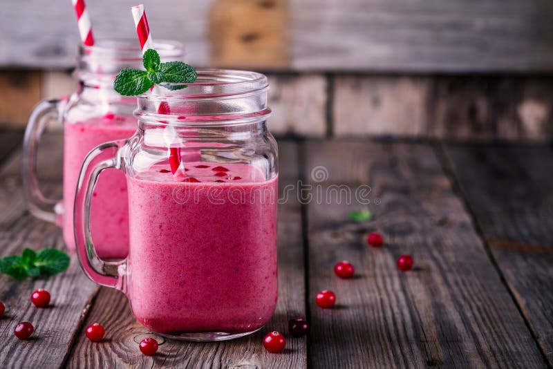 Розовый smoothie с одичалыми клюквами в опарнике каменщика с мятой и соломой на деревянной предпосылке стоковое изображение rf