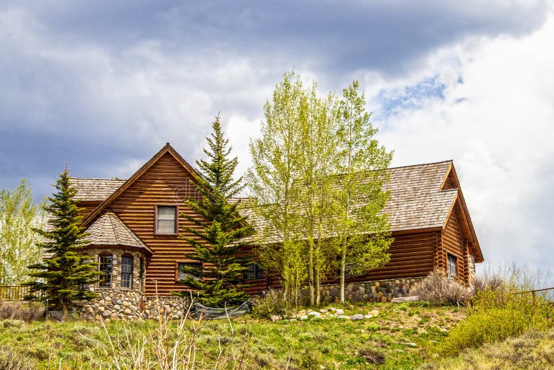 Luxury log cabin with wooden roof and rock bay window on hilltop surrounded by pines and quaking aspens. Luxury log cabin with wooden roof and rock bay window on hilltop surrounded by pines and quaking aspens.