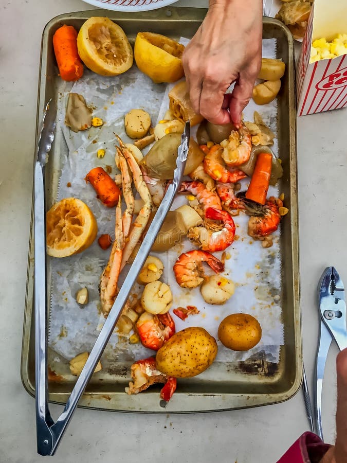 Рука ` s женщины достигая для кусочков обедающего чирея морепродуктов распространила вне на подносе с утварями стоковые фотографии rf Рука ` s женщины достигая для кусочков обедающего чирея морепродуктов распространила вне на подносе с утварями стоковые фотографии rf