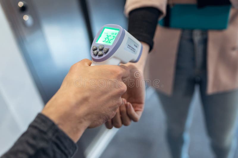 рука бизнес-леди проходит температурный контроль в коридоре офиса, чтобы предотвратить распространение covid19 стоковые изображения