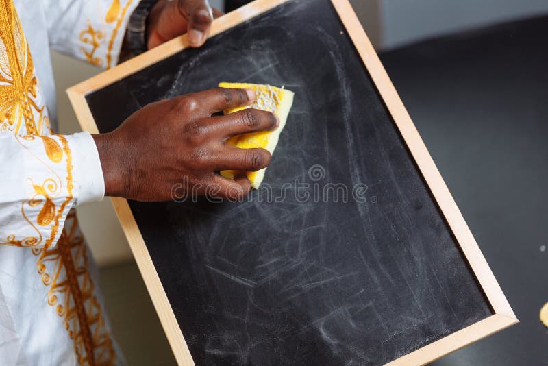 Hand in national clothes holding brush erase on black chalkboard and cleaning it. Hand in national clothes holding brush erase on black chalkboard and cleaning it..