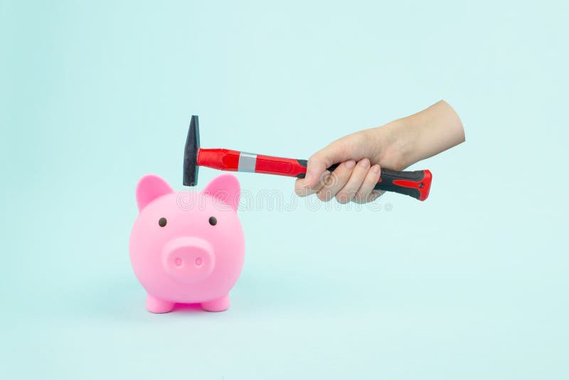 Hand With Hammer And Piggy Bank on blue background. Financial insecurity concept image. Hand With Hammer And Piggy Bank on blue background. Financial insecurity concept image.