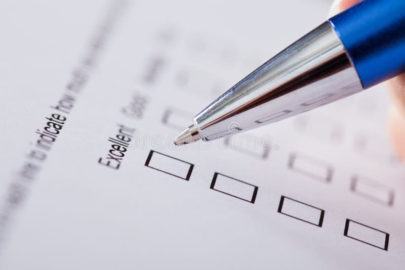 Close-up Of Hand Holding Pen Over Survey Form. Close-up Of Hand Holding Pen Over Survey Form