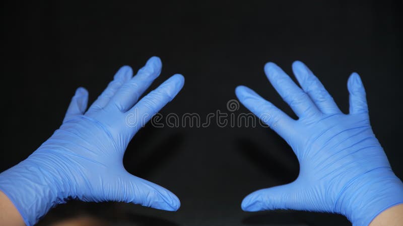 COVID-19 Two hands covered in blue surgical gloves, pointing forward, fingers apart, on black background, symbol of sanitary hygiene in the face of viruses such as covid 19, sars cov 2, coronavirus ... germs, bacteria, fungi. COVID-19 Two hands covered in blue surgical gloves, pointing forward, fingers apart, on black background, symbol of sanitary hygiene in the face of viruses such as covid 19, sars cov 2, coronavirus ... germs, bacteria, fungi