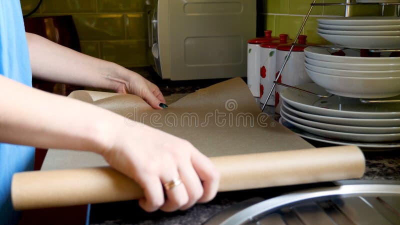 Руки взгляда дня женские устанавливая бумагу выпечки на олове подноса печи