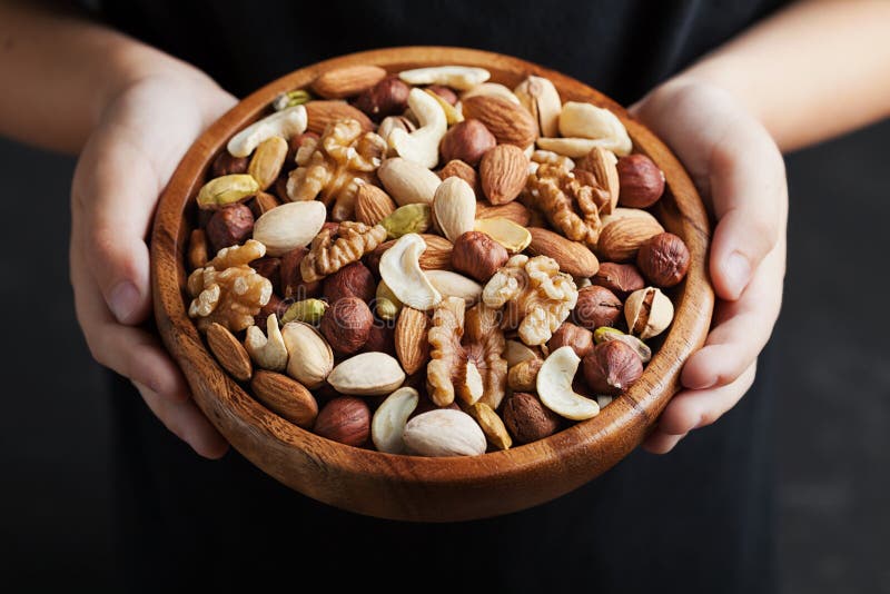 Childrens hands holding a wooden bowl with mix nuts. Healthy food and snack. Walnut, pistachios, almonds, hazelnuts and cashews. Childrens hands holding a wooden bowl with mix nuts. Healthy food and snack. Walnut, pistachios, almonds, hazelnuts and cashews.