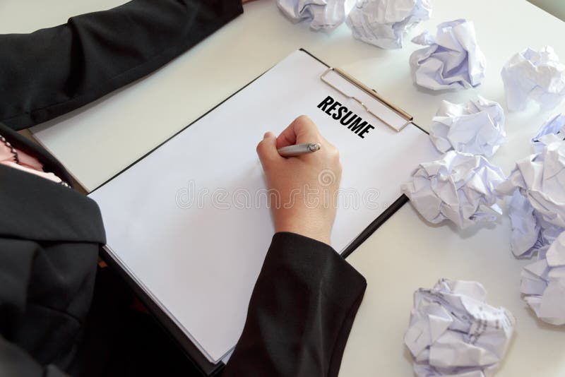 Hands of female writing resume with crumple sheets of papers at the office desk. Hands of female writing resume with crumple sheets of papers at the office desk.