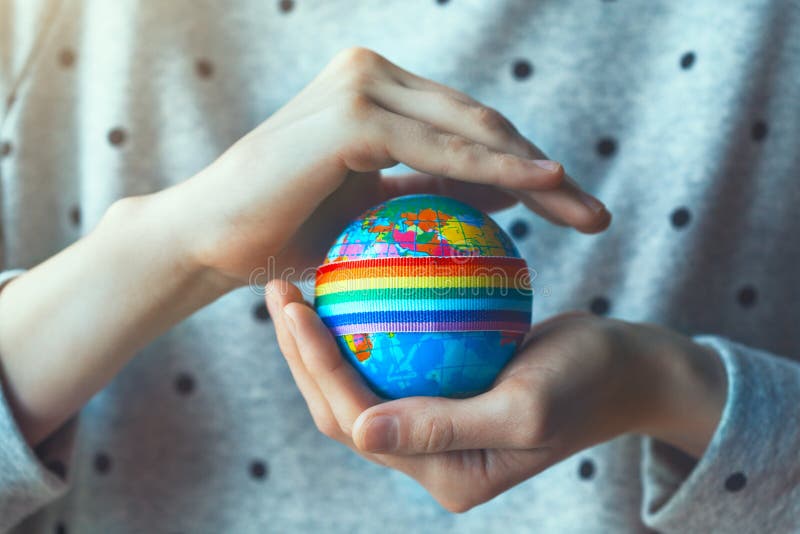 Руки женщины держа глобус с лентой радуги LGBT стоковое изображение rf Руки женщины держа глобус с лентой радуги LGBT стоковое изображение rf