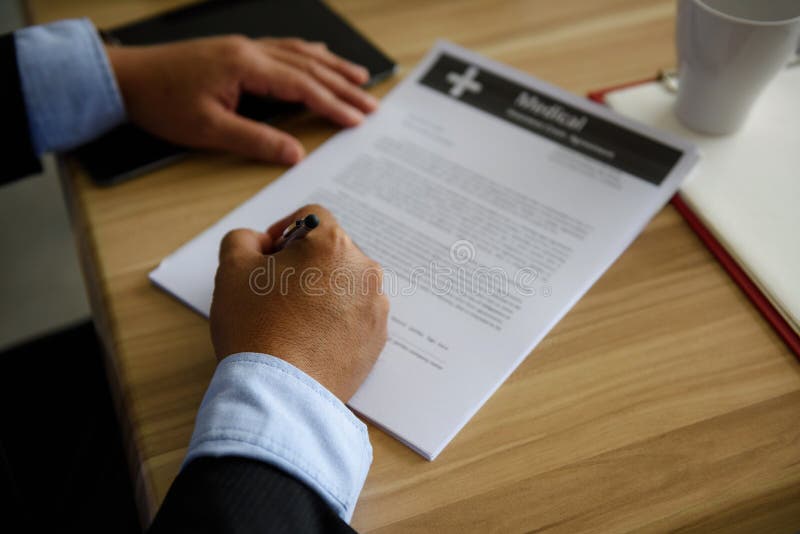 Closeup hands of Businessman CEO or Senior manager Signing Medical Contract Paper by Pen on wooden table in office. Business approach and achievement concept. Closeup hands of Businessman CEO or Senior manager Signing Medical Contract Paper by Pen on wooden table in office. Business approach and achievement concept.