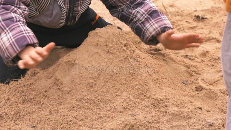 Руки маленького ребенка играя с песком