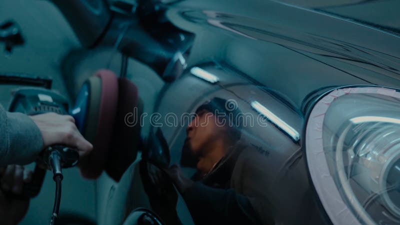 Руки работника воска автомобиля польские прикладывая защитную ленту перед полировать Buffing и полируя автомобиль Детализировать стоковая фотография rf Руки работника воска автомобиля польские прикладывая защитную ленту перед полировать Buffing и полируя автомобиль Детализировать стоковая фотография rf
