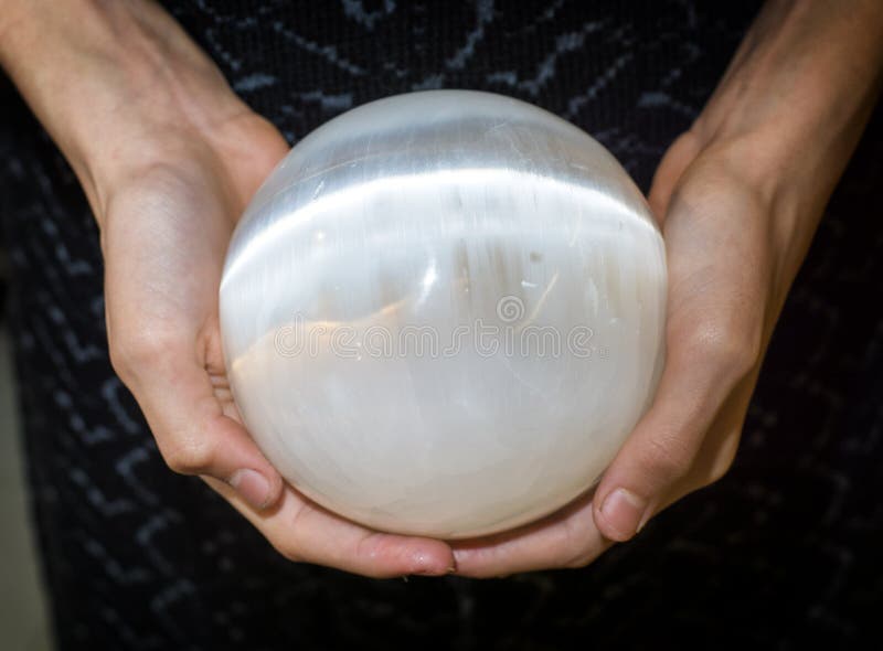 Close up shot of crop female hands holding sphere made of selenite or white quartz. Close up shot of crop female hands holding sphere made of selenite or white quartz.