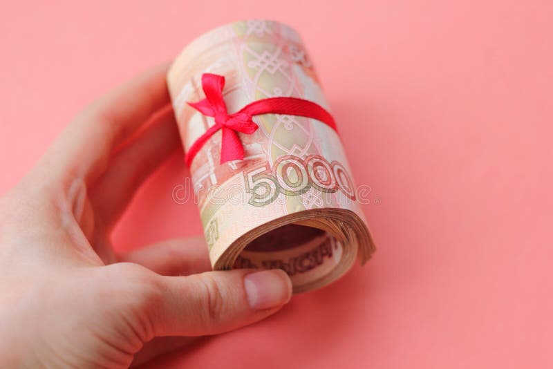 Русские деньги 5000 рублей переплетенных в трубку и связанных с лентой, на покрашенной предпосылке стоковое фото rf Русские деньги 5000 рублей переплетенных в трубку и связанных с лентой, на покрашенной предпосылке стоковое фото rf