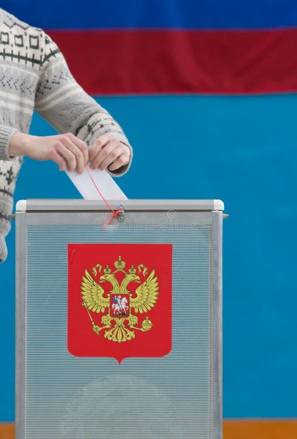 Русские президентские выборы - человек кладет избирательный бюллетень к голосуя коробке стоковое фото rf Русские президентские выборы - человек кладет избирательный бюллетень к голосуя коробке стоковое фото rf