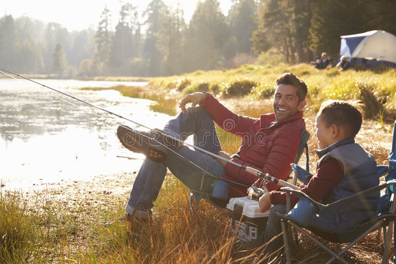 Father and son fishing by a lake, dad looks to camera. Father and son fishing by a lake, dad looks to camera