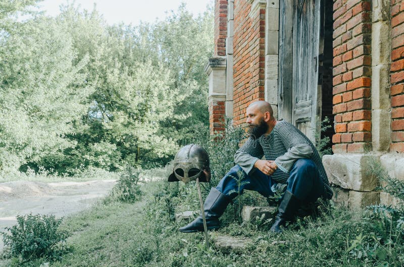 рядом со старым кирпичным замком и деревьями. меч и шлем. пенсивный вид. старая деревянная дверь стоковое фото rf