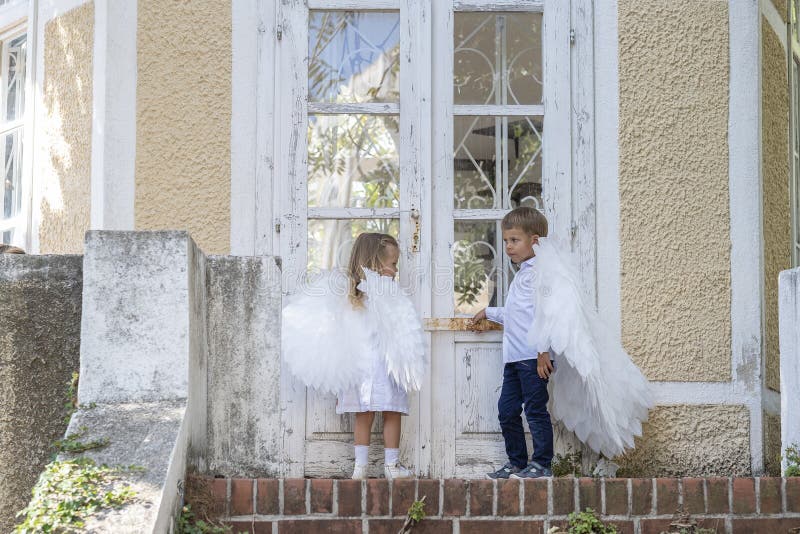 С niños vestidos como ángeles parados frente a una puerta cerrada fotos de archivo