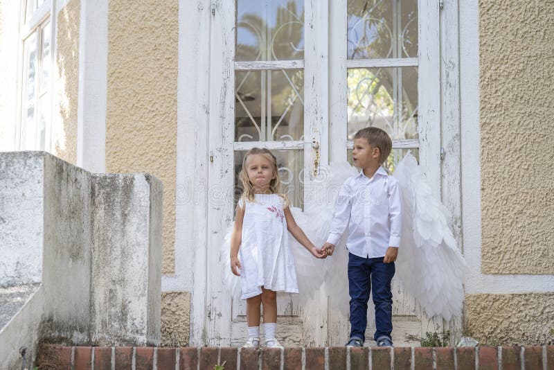 С niños vestidos como ángeles parados frente a una puerta cerrada fotos de archivo