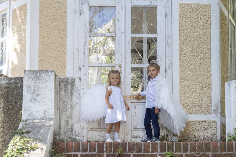 С niños vestidos como ángeles parados frente a una puerta cerrada fotografía de archivo