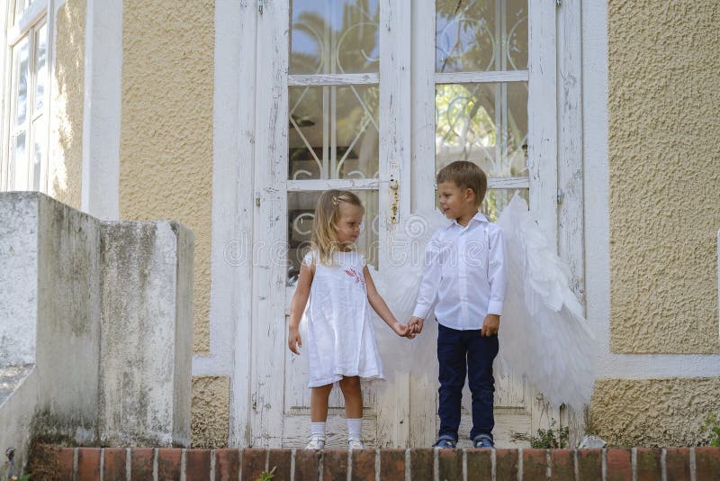 С niños vestidos como ángeles parados frente a una puerta cerrada imagenes de archivo