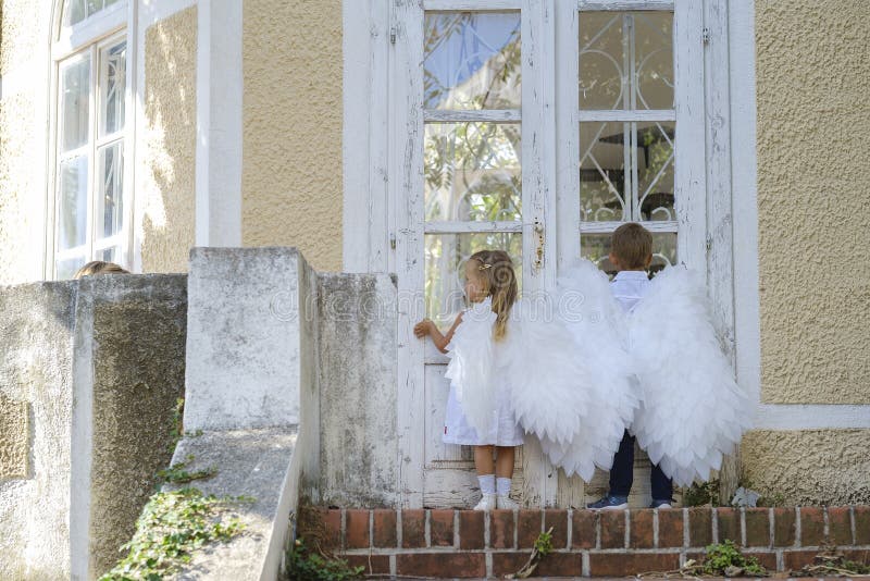 ? niños vestidos como ángeles parados frente a una puerta cerrada imagen de archivo libre de regalías