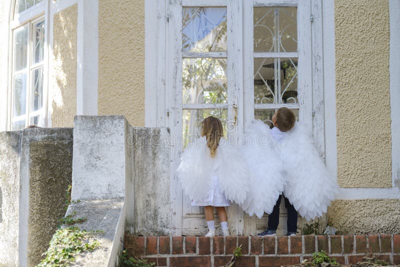 ? niños vestidos como ángeles parados frente a una puerta cerrada fotos de archivo